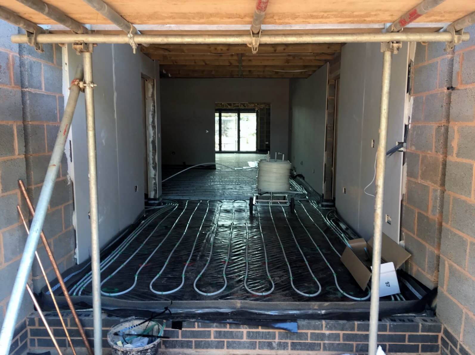 Underfloor heating system with a layer of self levelling screed applied in background