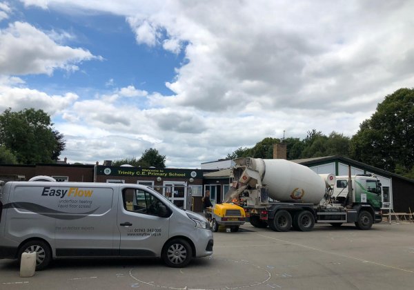 A Gyvlon screed mixing truck parked outside the school, next to a underfloor heating van