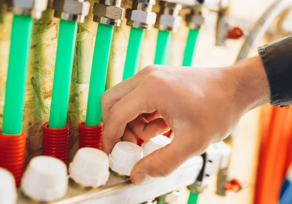 A plumber resolving an underfloor heating issue in the manifold