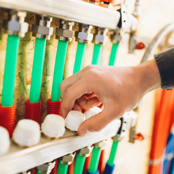 A plumber resolving an underfloor heating issue in the manifold