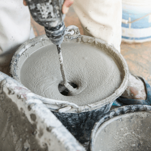 A DIY enthusiast mixing liquid screed in a bucket