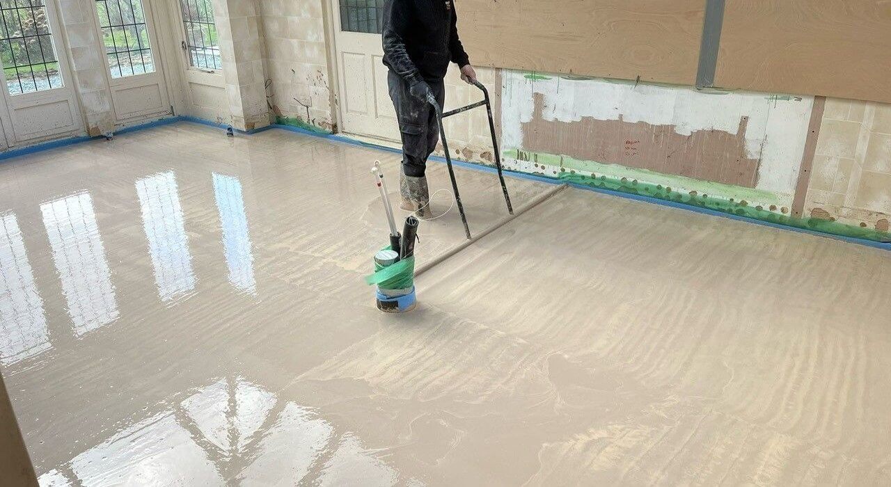A floor screeder tamping anhydrite screed to remove any bubbles