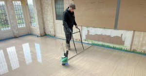 A floor screeder tamping anhydrite screed to remove any bubbles