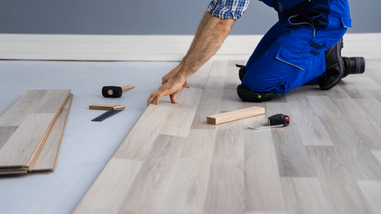 Engineered wood flooring being laid over floor screed containing underfloor heating pipes