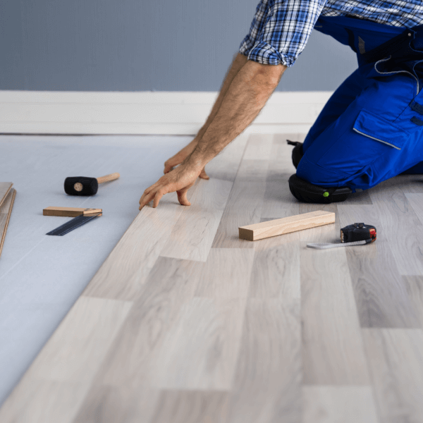 A builder laying wooden floor for underfloor heating