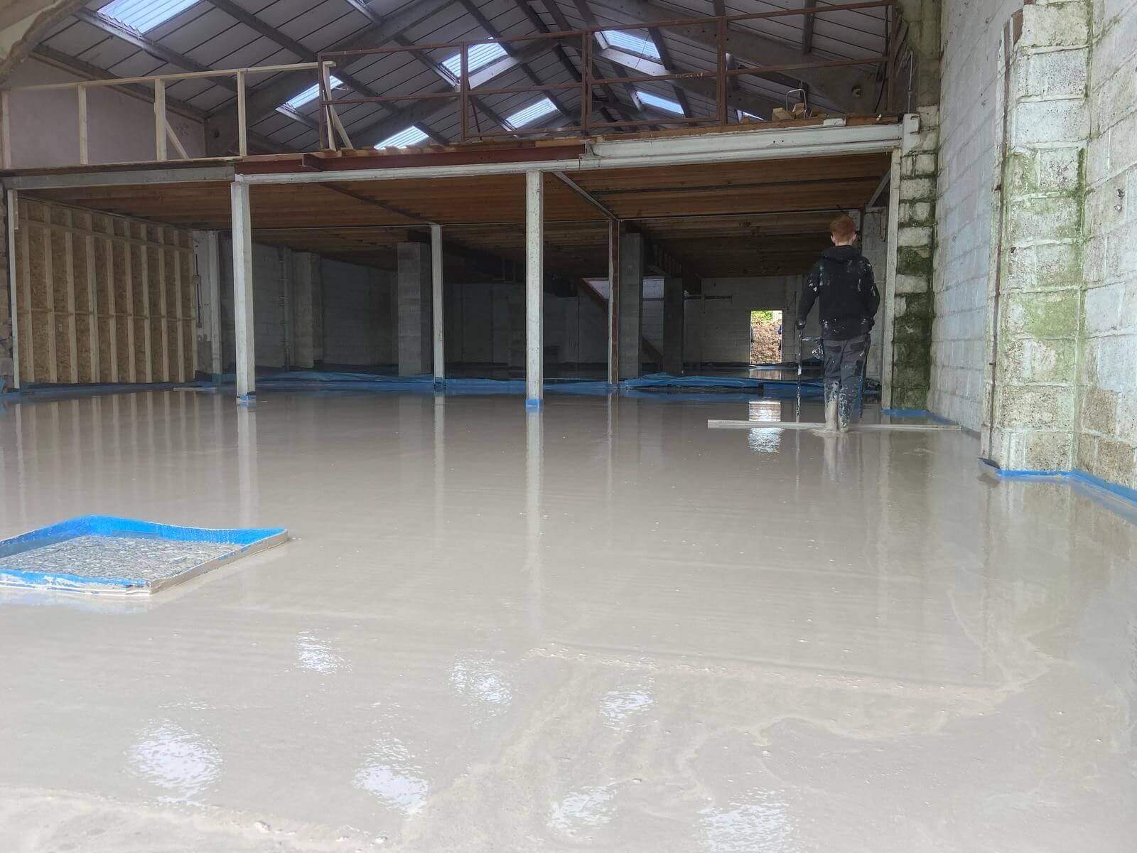 Liquid screed floor being levelled out by a young man