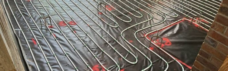 Underfloor heating pipes lay on black tarpaulin