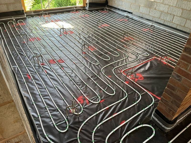 Underfloor heating pipes lay on black tarpaulin