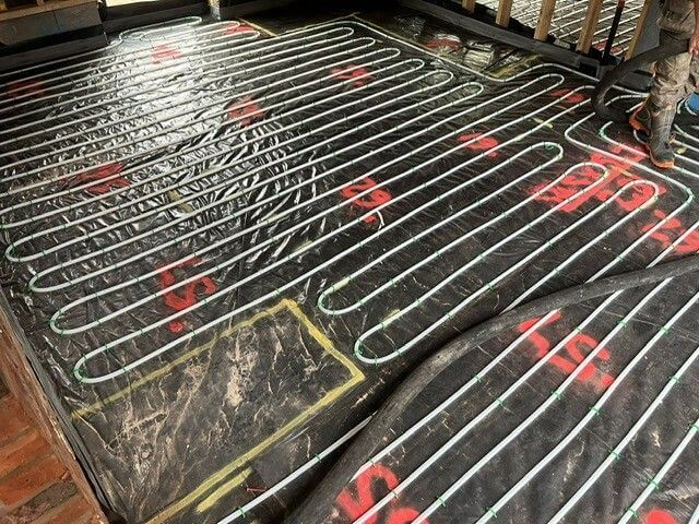 Close up of pipework installation of underfloor heating for wooden flooring
