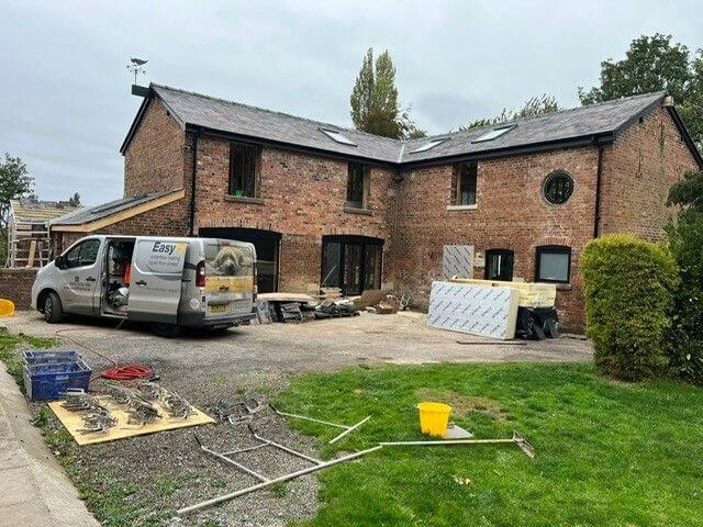 Underfloor heating installer van parked by a barn conversion