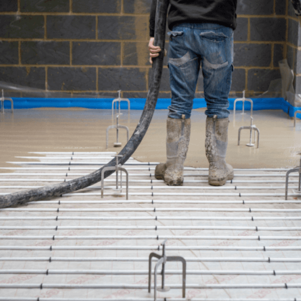 An Easyflow underfloor heating installer pouring liquid screed
